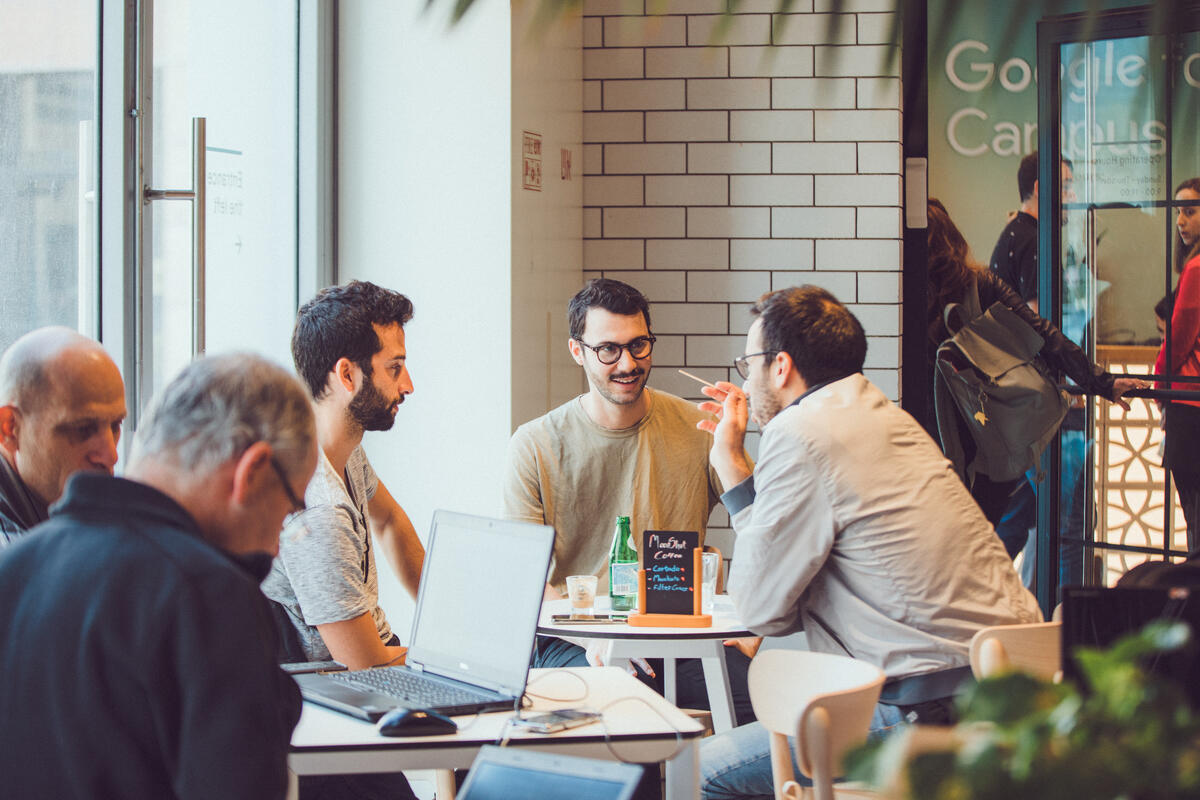Three guys sitting at table discussing