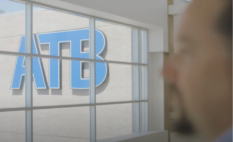 Logo des ATB auf einem Gebäude mit einem Mann, der nach außen blickt