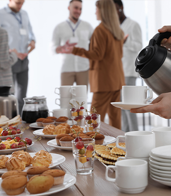 Close up of a continental breakfast at a business conference with blurred attendees wearing lanyards in the background Close up of a continental breakfast at a business conference with blurred attendees wearing lanyards in the background